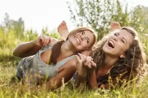 Two young women laughing in a field together.
