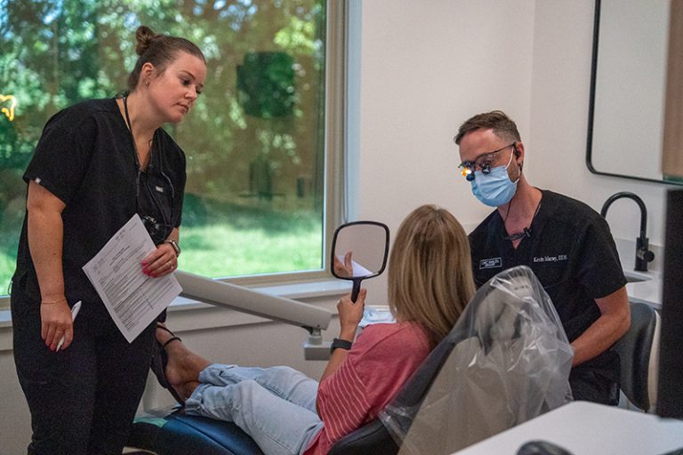 OKC Smiles team with a patient examining their cosmetic dentistry results.